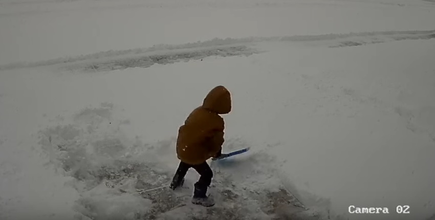 Un petit garçon pas très ravi de devoir nettoyer son allée pleine de neige !